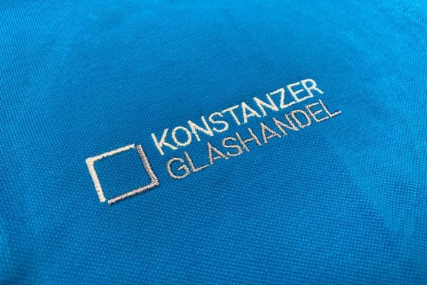 Mitarbeiter präsentieren Arbeitskleidung, die durch textil druck individuell gestaltet wurde.