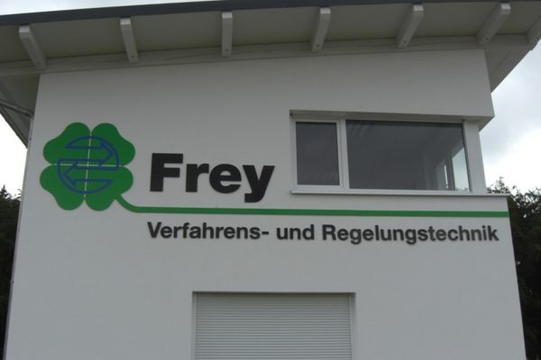 Metallschriftzug mit Logoelementen auf Betonfassade