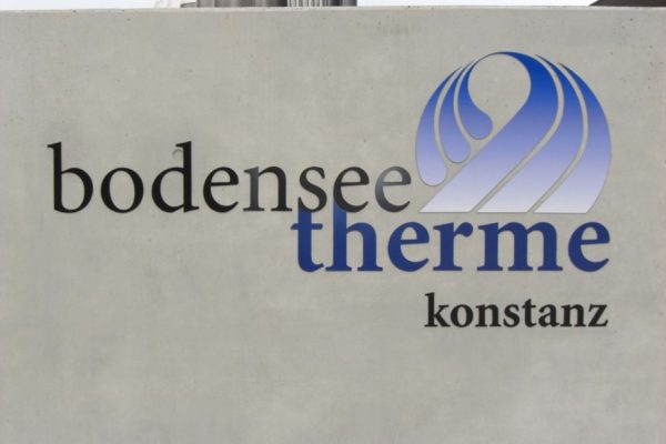 Schriftzug + Logo aus Metall gefertigt und auf Betonfläche montiert