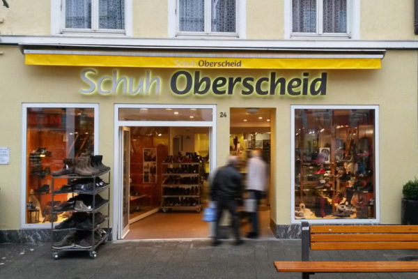Lichtreklame auf Betonfassade für ein Schuhgeschäft